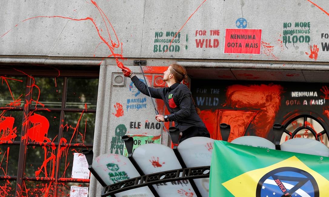 Ativista joga tinta vermelha sobre a fachada da embaixada durante protesto contra a mudanÃ§a climÃ¡tica Foto: PETER NICHOLLS / REUTERS