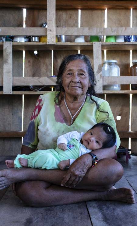 Dona Zilda Paumari, 80 anos, é a mulher mais idosa da aldeia Patauá — uma das sete aldeias dos Paumari — e leva no colo a mais jovem integrante da aldeia, sua bisneta Kemily, nascida no último maio Foto: Marizilda Cruppe
