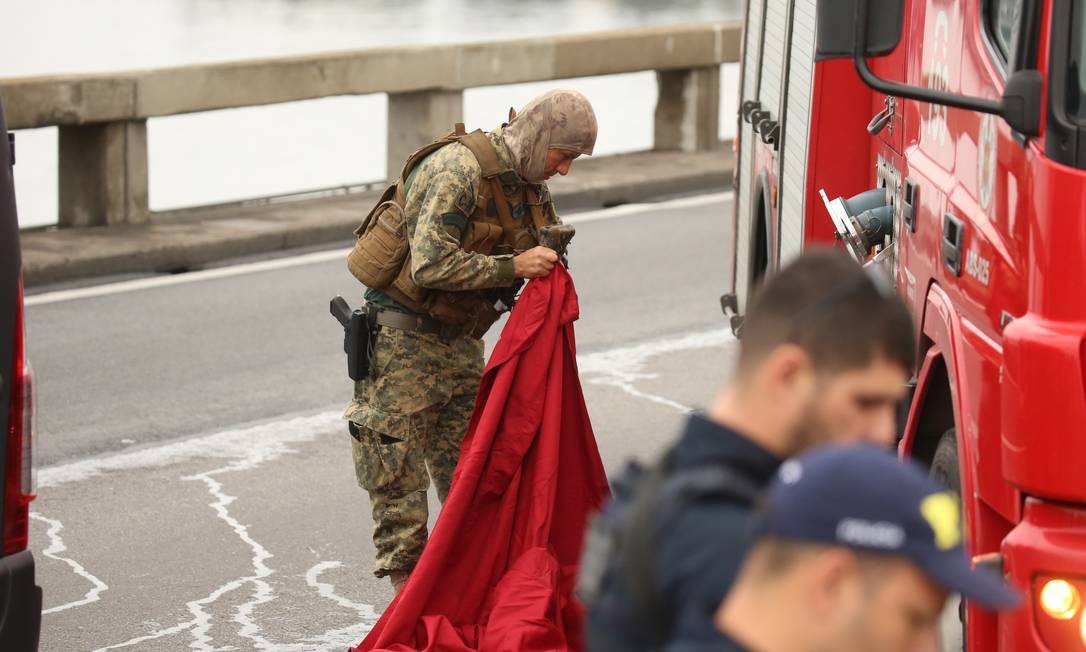 Sniper do Bope prepara manta vermelha para se camuflar em cima de veículo dos bombeiros Foto: Fabiano Rocha / Agência O Globo