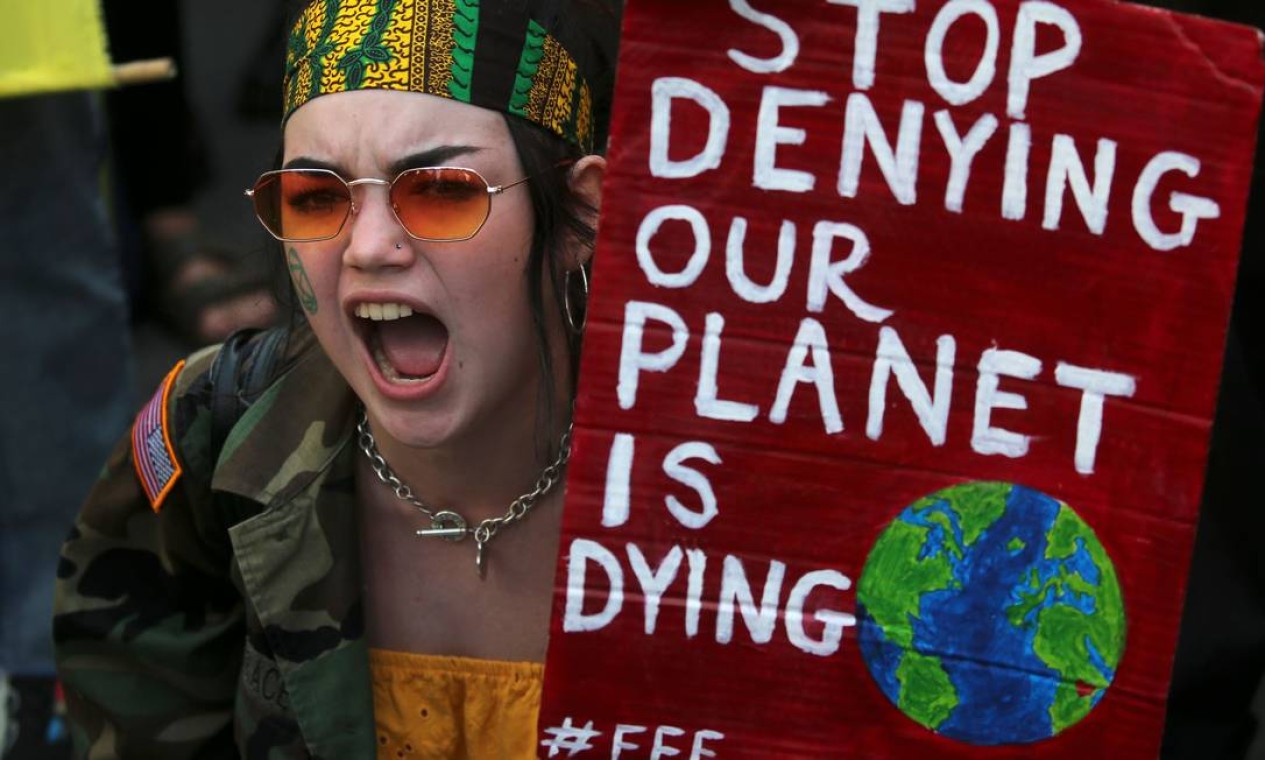 Manifestante segura cartaz que diz "pare de negar que nosso planeta está morrendo" durante manifestação no centro de Londres Foto: ISABEL INFANTES / AFP
