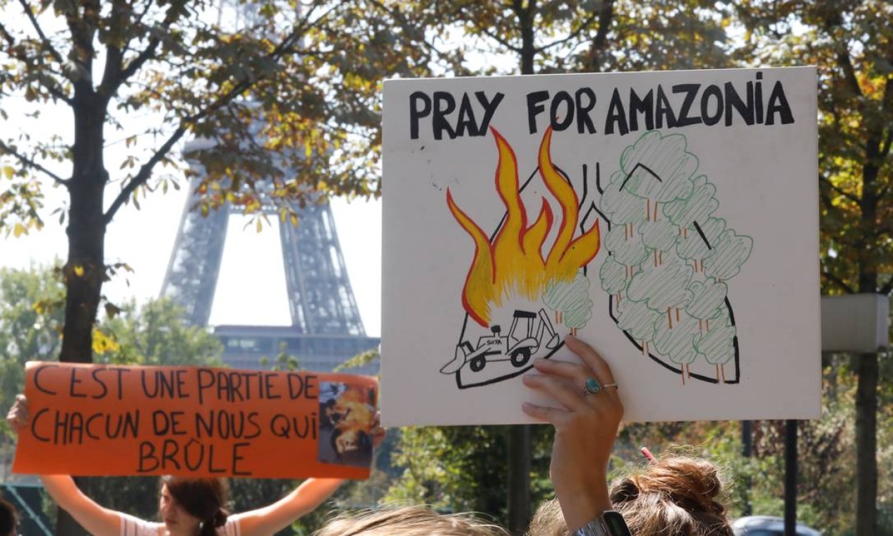 Manifestantes erquem cartazes com os dizeres "Ore pela Amazônia" e "É uma parte de cada um de nós que queima" durante protesto em Paris, na França, em frente à embaixada brasileira Foto: CHARLES PLATIAU / REUTERS