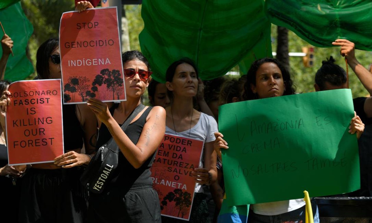 Ativistas exibem cartaz com a inscrição "Pare o genocídio dos povos indígenas" durante uma manifestação em Barcelona Foto: LLUIS GENE / AFP
