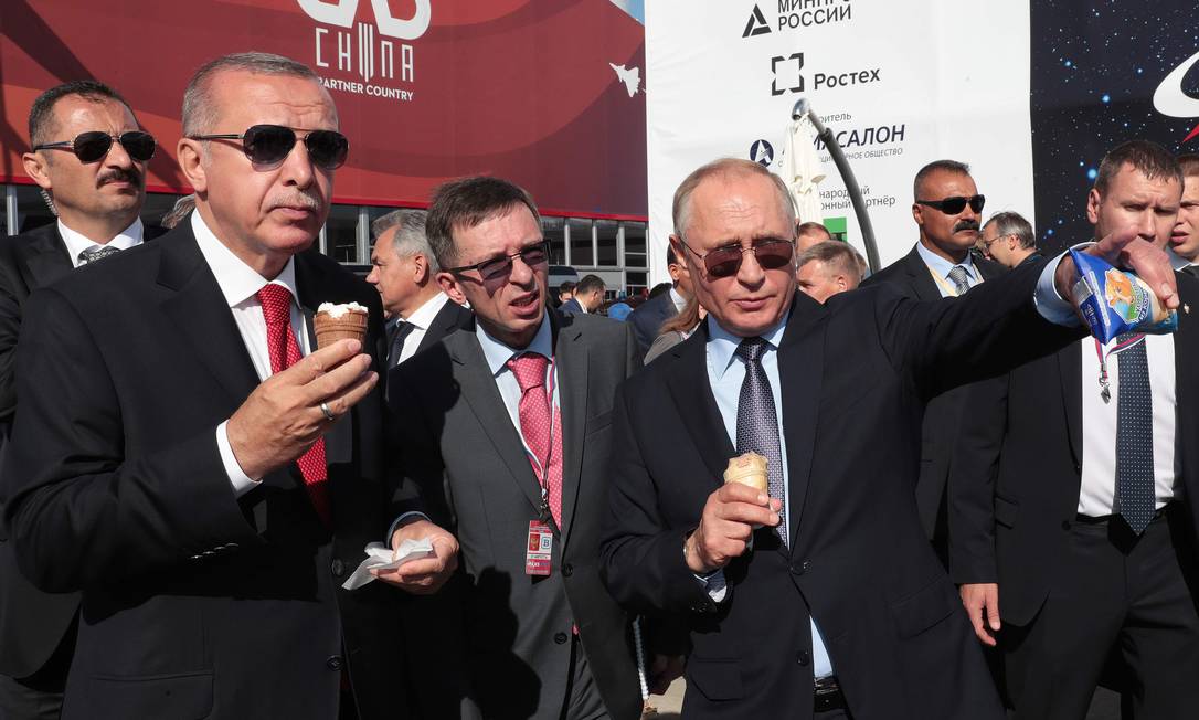 Com sorvetes em mãos, Recep Tayyip Erdogan e Vladimir Putin observam as aeronaves na feira aérea MAKS, nos arredores de Moscou. Turquia sinalizou que pode comprar caças russos, deixando de lado os F-35 dos EUA Foto: HANDOUT / AFP