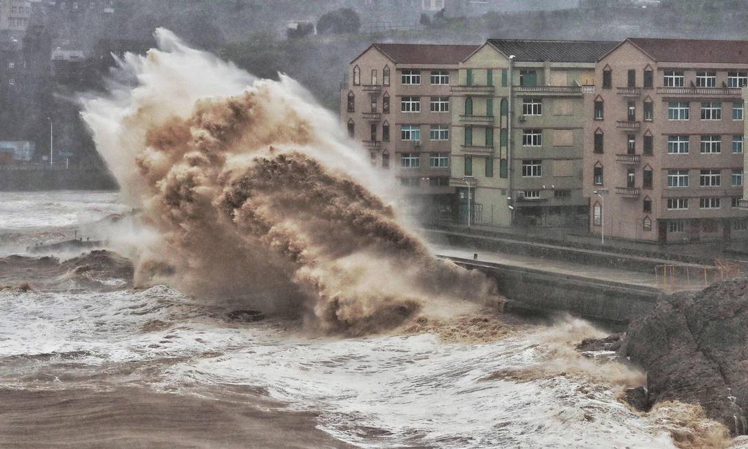 Ondas atingem um paredão em frente a edifícios em Taizhou, província de Zhejiang, leste da China. Os mesmos oceanos que nutriram a evolução humana estão prontos para desencadear a miséria em escala global alerta um projeto de relatório da ONU Foto: - / AFP