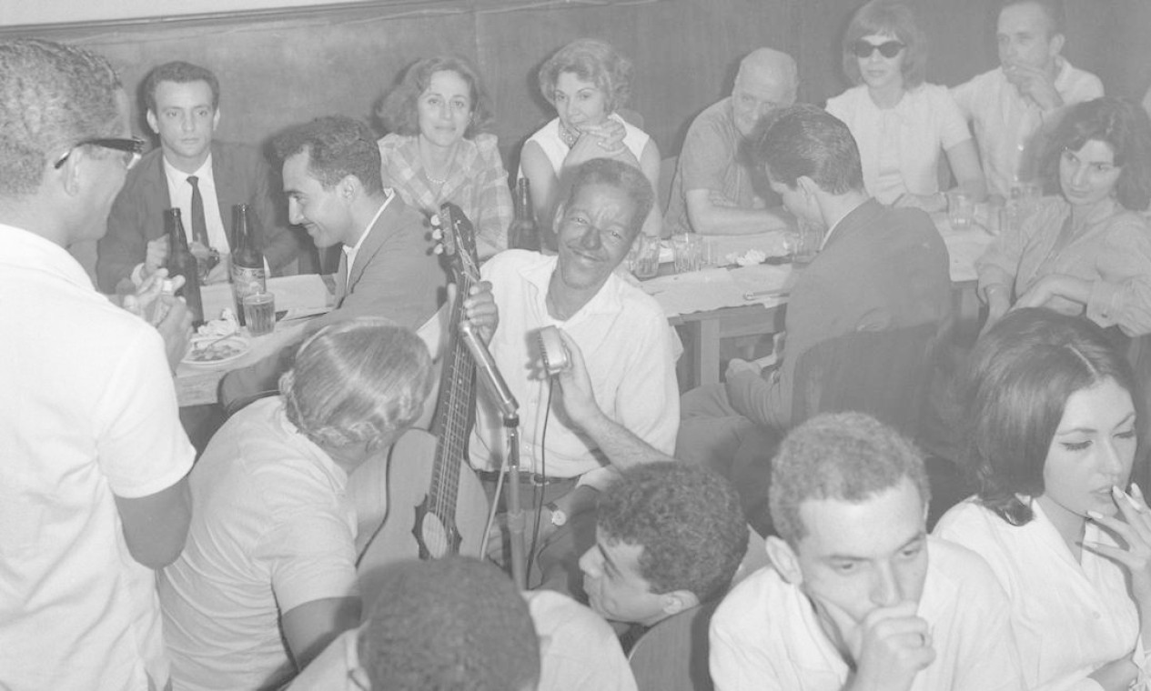 No Bar e Restaurante Zicartola, em fevereiro de 1964, Elton Medeiros (de pé), com os compositores Nelson Cavaquinho (de costas, segurando o violão) e Cartola (de frente, cantando) Foto: Agência O Globo
