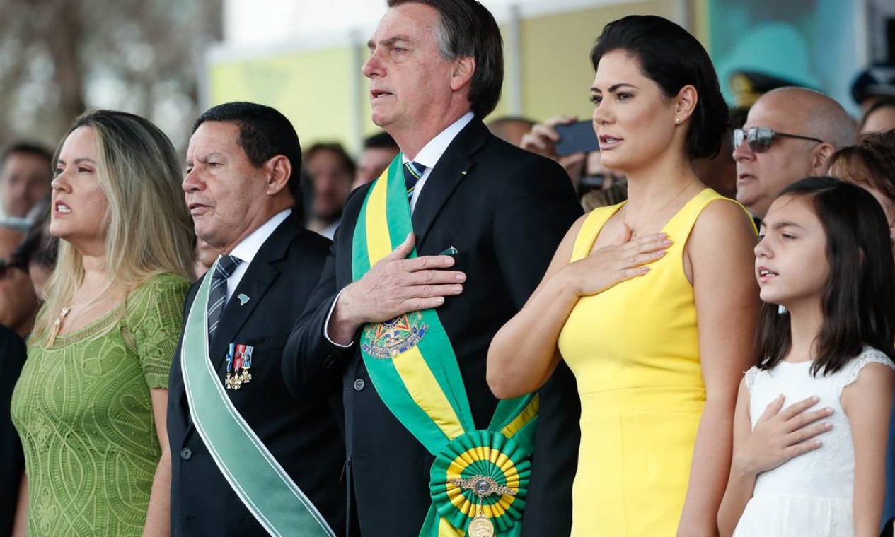 Bolsonaro canta o hino nacional na tribuna presidencial da solenidade ao lado do vice-presidente Hamilton Mourão (à esquerda) e da primeira-dama Michelle Bolsonaro e da filha Laura (à direita) Foto: Isac Nóbrega / PR