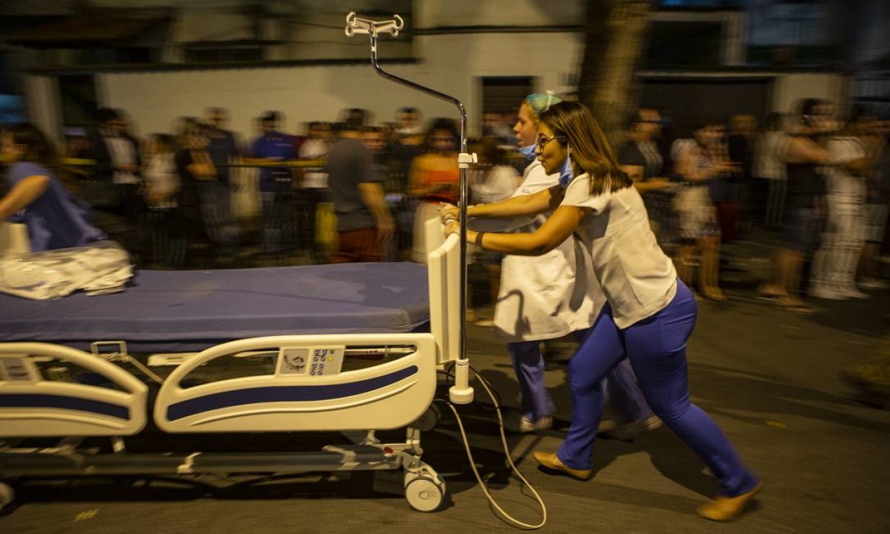 Funcionários levam cama hospitalar para acomodar paciente durante o incêndio Foto: Alexandre Cassiano / Agência O Globo