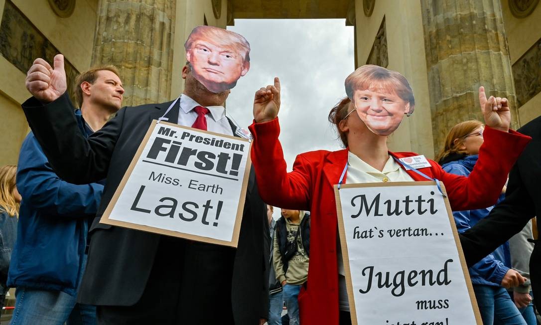 No Portão de Brandemburgo, em Berlim, Alemanha, manifestantes com máscaras do presidente dos EUA, Donald Trump, e da chanceler alemã, Angela Merkel, exibem cartazes dizendo "Sr. Presidente Primeiro, Sra. Earth Last" (E) e "Mutti (Mãe, que significa Merkel) vocês não conseguiram, os jovens precisam consertar" no protesto "Sextas-feiras para o futuro" contra mudanças climáticas Foto: JOHN MACDOUGALL / AFP