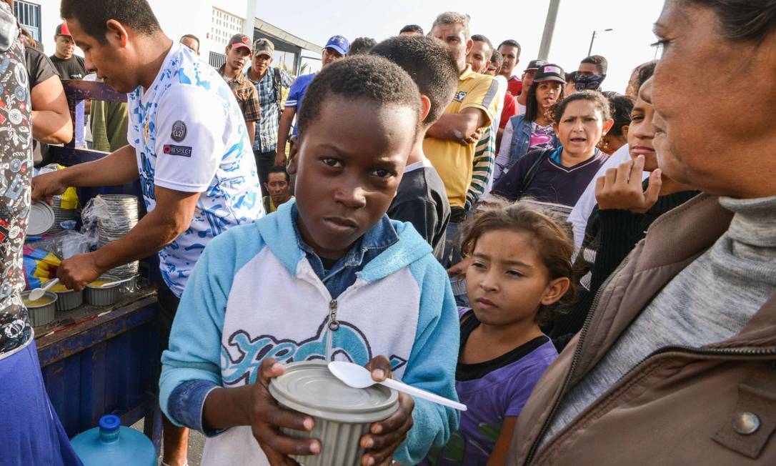 Venezuelanos recebem comida de voluntários enquanto aguardam autorização para entrar no Peru Foto: CRIS BOURONCLE / AFP / 23-08-2018