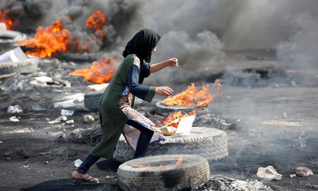
Uma manifestante corre entre pneus queimados durante um toque de recolher, dois dias após protestos contra o governo que se tornarem violentos em Bagdá
Foto:
WISSM AL-OKILI
/
REUTERS

