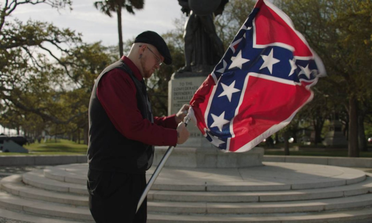 Partidário do South Carolina Secessionist Party, o americano James Bessenger abre sua bandeira dos Estados Confederados em cena do documentário 'Por que odiamos?': associado à escravidão, estandarte é considerado símbolo racista nos Estados Unidos Foto: Discovery Channel