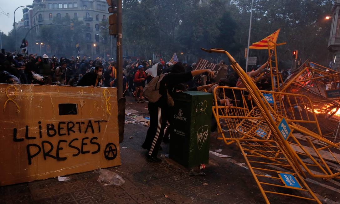 Manifestantes montam barricadas nas ruas de Barcelona em meio a novos confrontos com a polícia. Em uma das barreiras o pedido para que os 9 ativistas condenados a até 13 anos de prisão sejam libertados Foto: PAU BARRENA / AFP