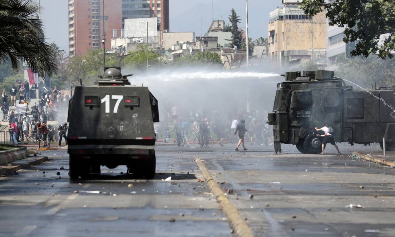 Jatos de água são lançados em manifestantes por carros da polícia na capital do Chile Foto: IVAN ALVARADO / REUTERS