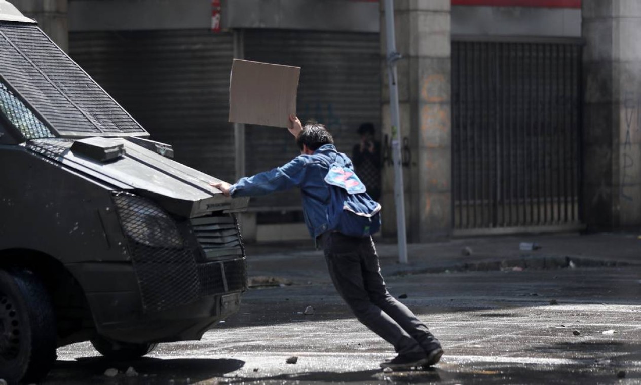 Manifestante para veículo blindado da polícia em Santiago Foto: IVAN ALVARADO / REUTERS