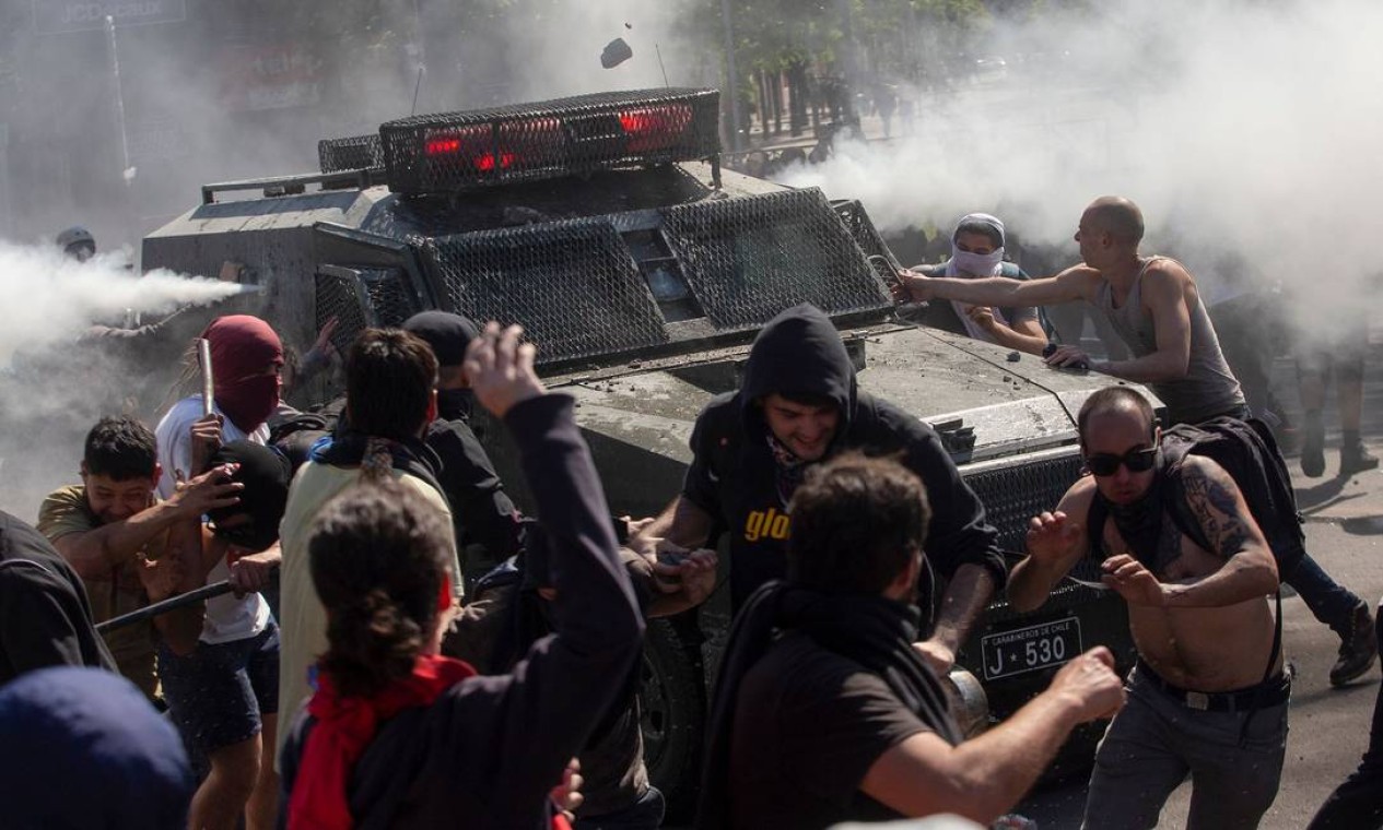 Manifestantes cercam um veículo policial durante protestos em Santiago Foto: CLAUDIO REYES / AFP