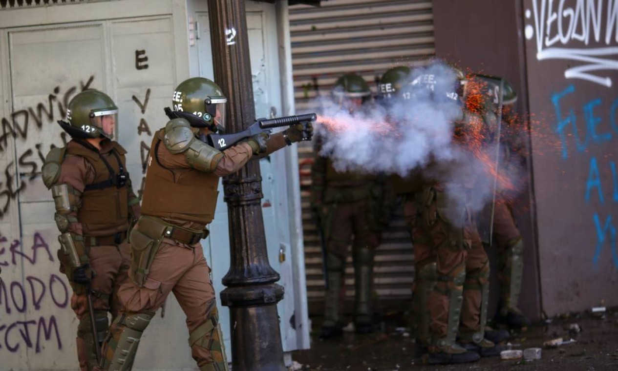 Policial dispara bomba de gás lacrimogêneo em direção aos manifestantes Foto: PABLO VERA / AFP