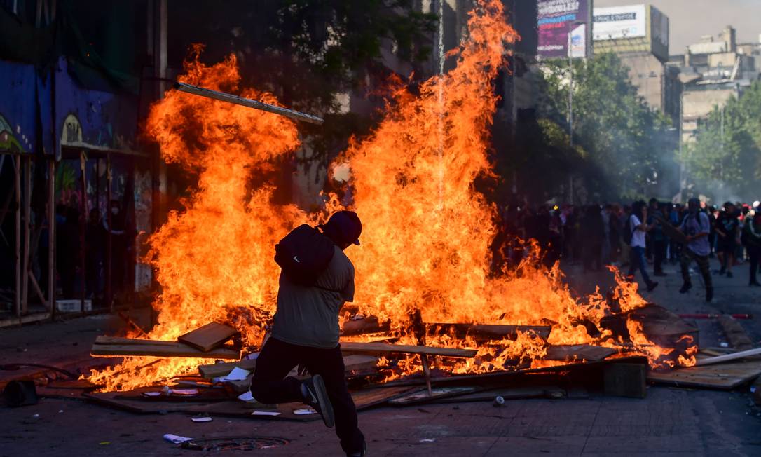 Manifestantes queimam entulho em rua de Santiago durante mais um dia de protestos na cidade Foto: MARTIN BERNETTI / AFP