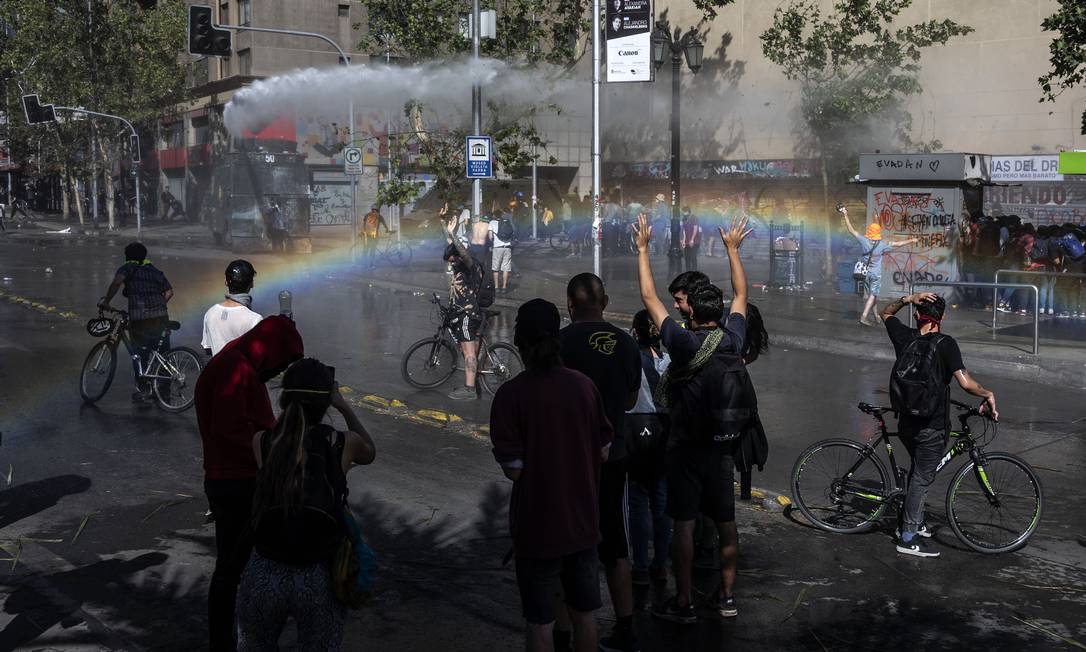 Caminhão da polícia joga água em manifestantes durante ato em Santiago, no quinto dia consecutivo de violência nas ruas do Chile Foto: PEDRO UGARTE / AFP