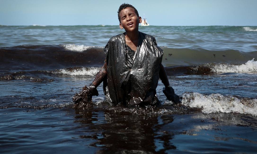 Menino sai do mar repleto de óleo no Cabo de Santo Agostinho, em Pernambuco Foto: LEO MALAFAIA / AFP