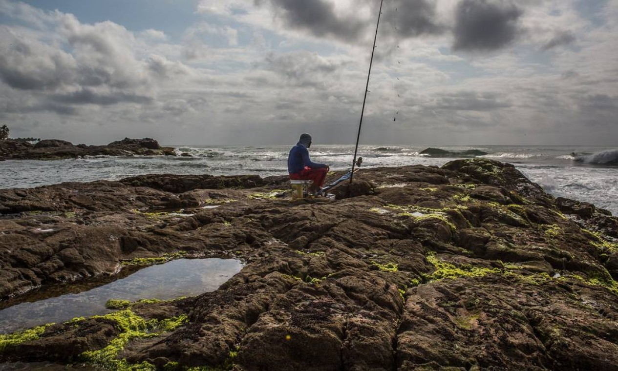 Um pescador é visto em uma rocha coberta de petróleo na praia de Pedra do Sal, em Salvador, Bahia Foto: Antonello Veneri / AFP - 23/10/2019