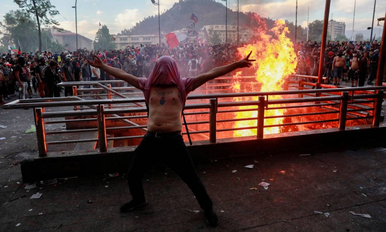 Manifestante diante de uma entrada do metrô: barreiras com fogo Foto: HENRY ROMERO / REUTERS