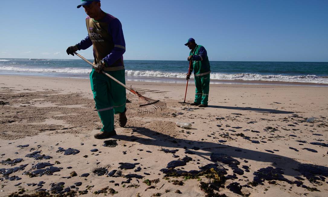 Agentes limpam óleo na Praia da Pituba, em Salvador Foto: Luca Castro/Fotoarena/Agência O Globo