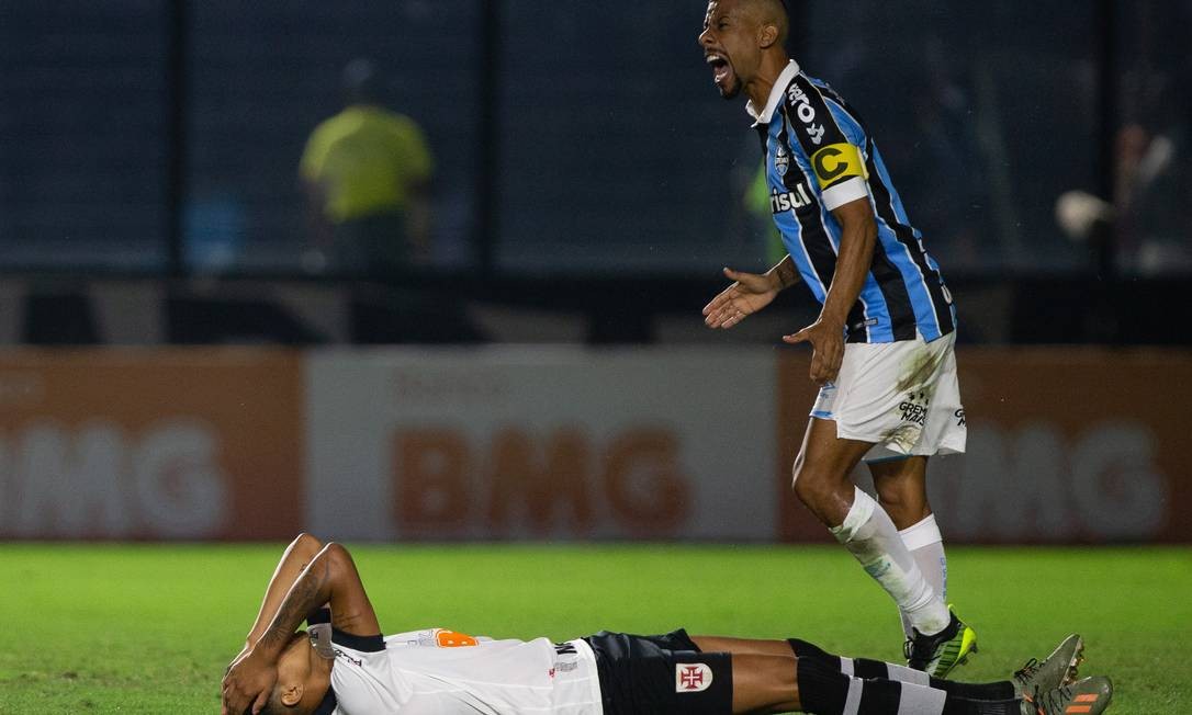 Marrony no chão enquanto Leo Moura comemora um dos gols do Grêmio em São Januário Foto: Marcelo Goncalves/Photo Premium
