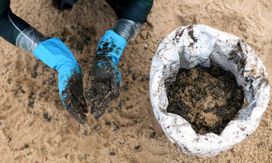 Agente municipal trabalha para remover óleo bruto na Barra de Jacuipe, Camaçari, Bahia Foto: Lucas Landau / Reuters