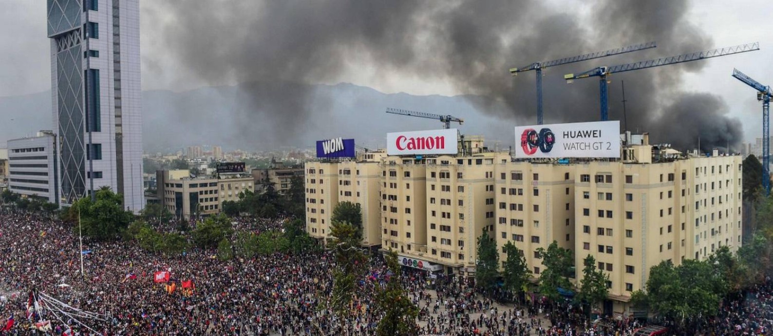 Fumaça da Universidade Pedro de Valdivia, incendiada por mascarados, é vista durante grande marcha na Praça Itália Foto: MARTIN BERNETTI / AFP