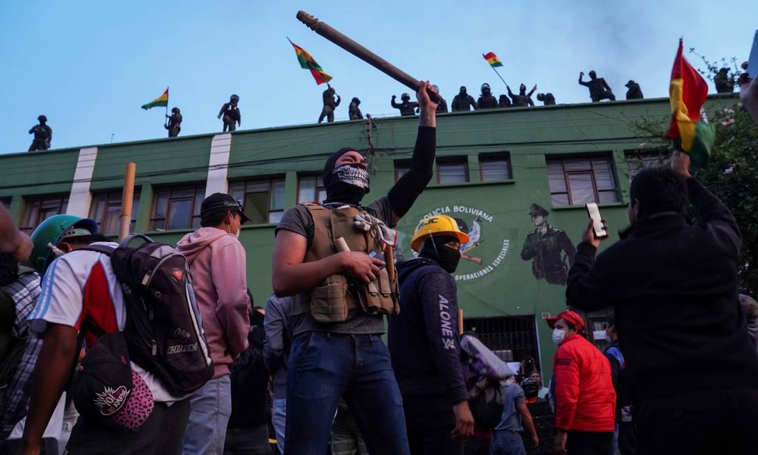 Policiais no telhado e manifestantes no chão protestam contra Morales em Cochabamba, Bolívia Foto: DANILO BALDERRAMA / REUTERS