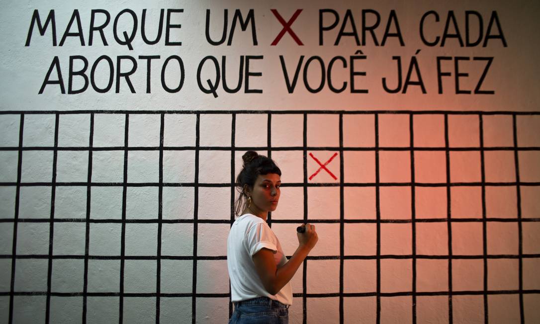 Aleta Valente e a obra 'Marque um x para cada aborto que você já fez', na parede da galeria Foto: Gabriel Monteiro / Agência O Globo