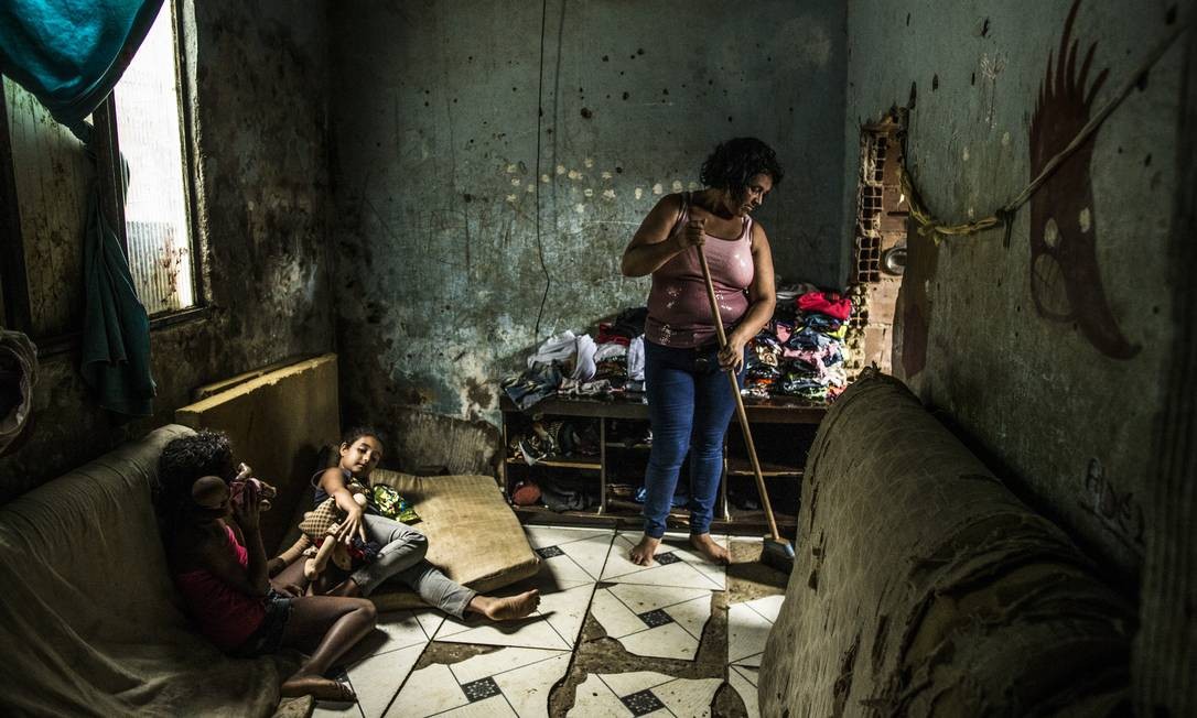 Lucineia da Silva Machado varre a casa: sua família, que vive em Magé, enfrenta dificuldades para suprir necessidades básicas Foto: Guito Moreto / Agência O Globo