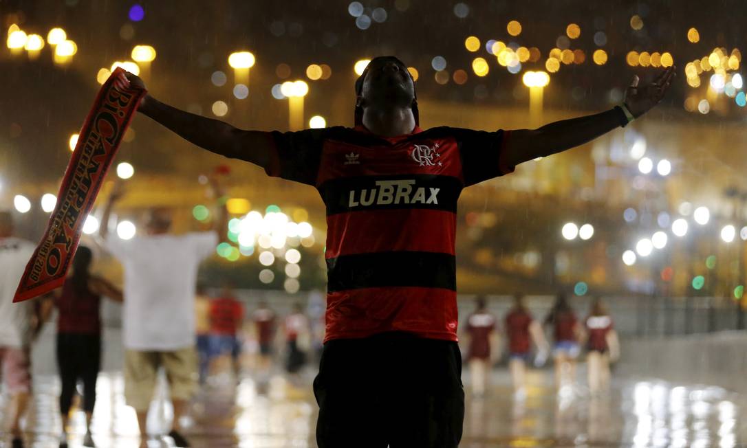 De corpo e alma lavados pela chuva, torcedor do Flamengo comemora título de campeão da América na saída do estádio Maracanã Foto: MARCELO THEOBALD / Agência O Globo