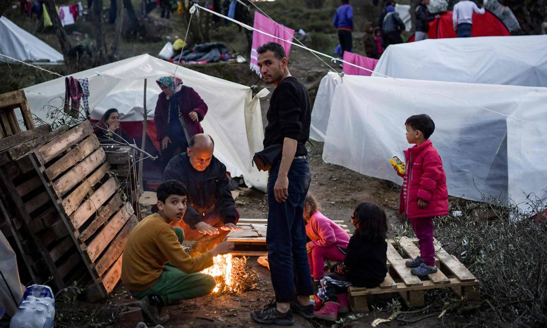 Família em volta de fogueira no acampamento de Moria, na ilha grega de Lesbos Foto: ARIS MESSINIS / AFP
