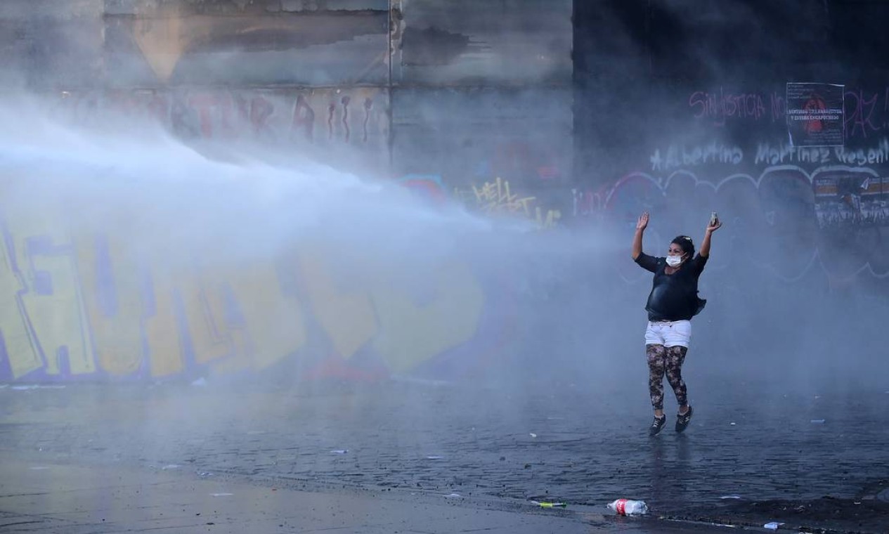 Um manifestante é atingido por um canhão de água durante protesto em Santiago Foto: JOHAN ORDONEZ / AFP