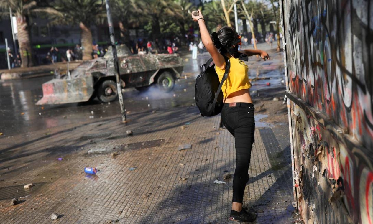 Uma manifestante atira pedra contra policiais durante protesto contra o governo chileno, em Santiago Foto: PABLO SANHUEZA / REUTERS