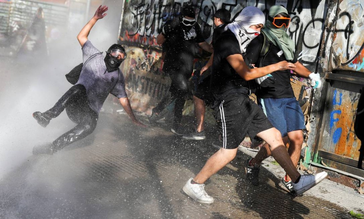Manifestante cai ao ser atingido por um jato de água das forças de segurança durante protesto contra o governo do Chile, em Santiago Foto: PABLO SANHUEZA / REUTERS