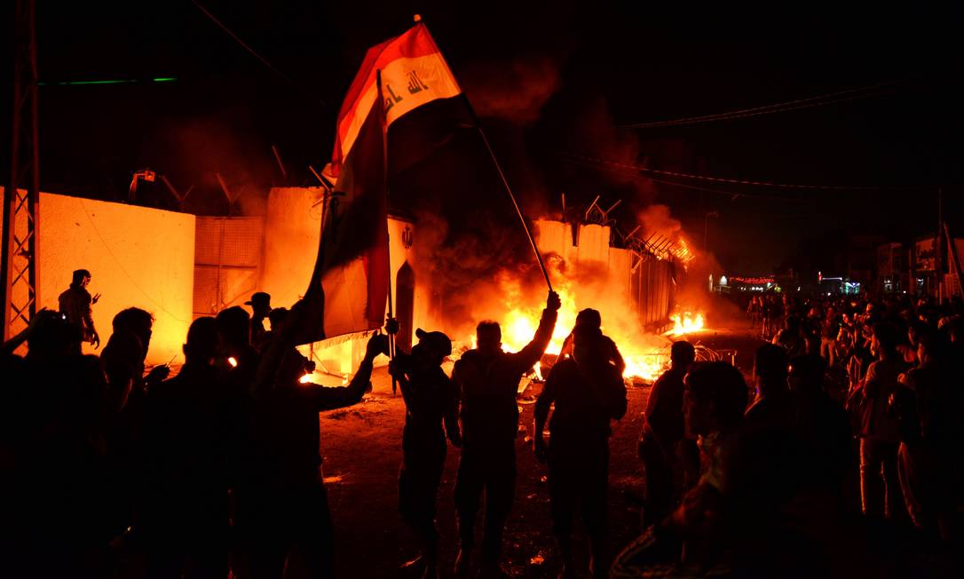 Manifestantes iraquianos ao redor de chamas no consulado do Irã em Najaf Foto: AFP/27-11-2019