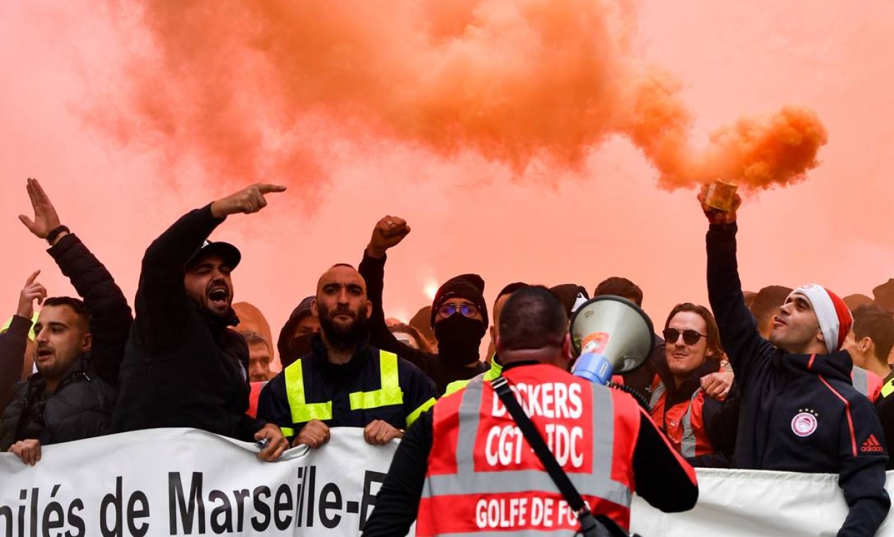 Os portuários marcham com bombas de fumaça e seguram uma faixa enquanto participam de uma manifestação para protestar contra a reforma das aposentadorias, em Marselha, Sul Foto: Clement Mahoudeau / AFP