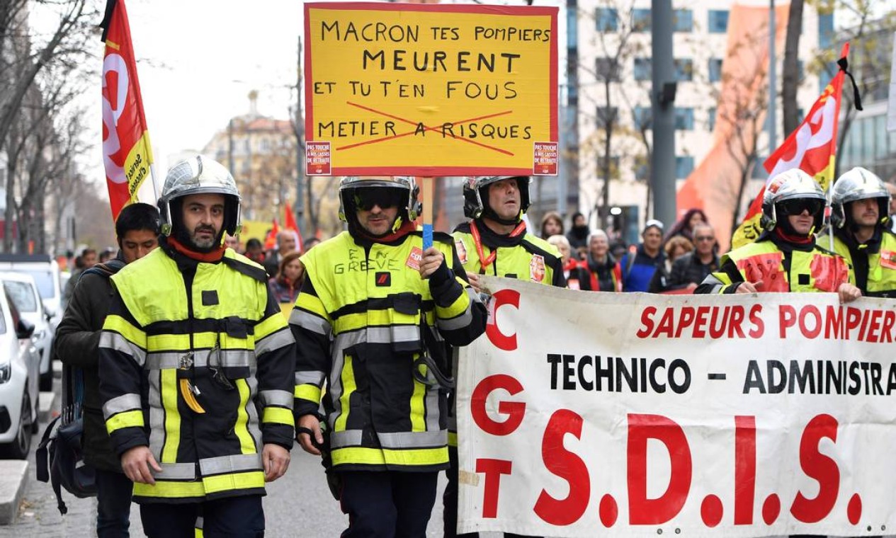 "Macron, seus bombeiros estão morrendo, e você não se importa", diz o cartaz segurado pela categoria que também aderiu a greve. Reforma propõe fim de 42 aposentadorias especiais Foto: Clement Mahoudeau / AFP