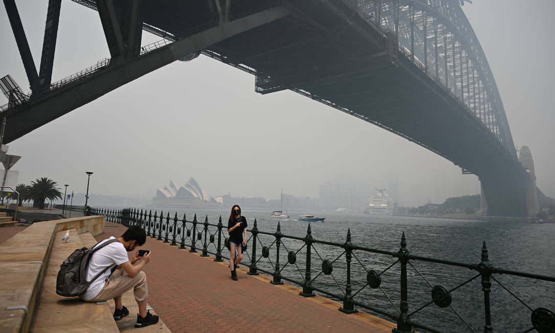Turistas usam máscaras na Ponte Harbour, em Sydney, para se proteger na fumaça tóxica que tomou conta da cidade e levou mais de 20 mil pessoas aos hospitais Foto: PETER PARKS / AFP