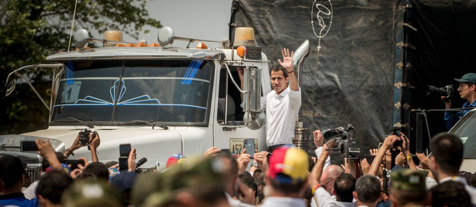 O líder opositor Juan Guaidó acena a apoiadores na cidade colombiana de Norte de Santander durante entrega de ajuda humanitária à Venezuela: tentativa de se reeleger hoje Foto: MERIDITH KOHUT / NYT