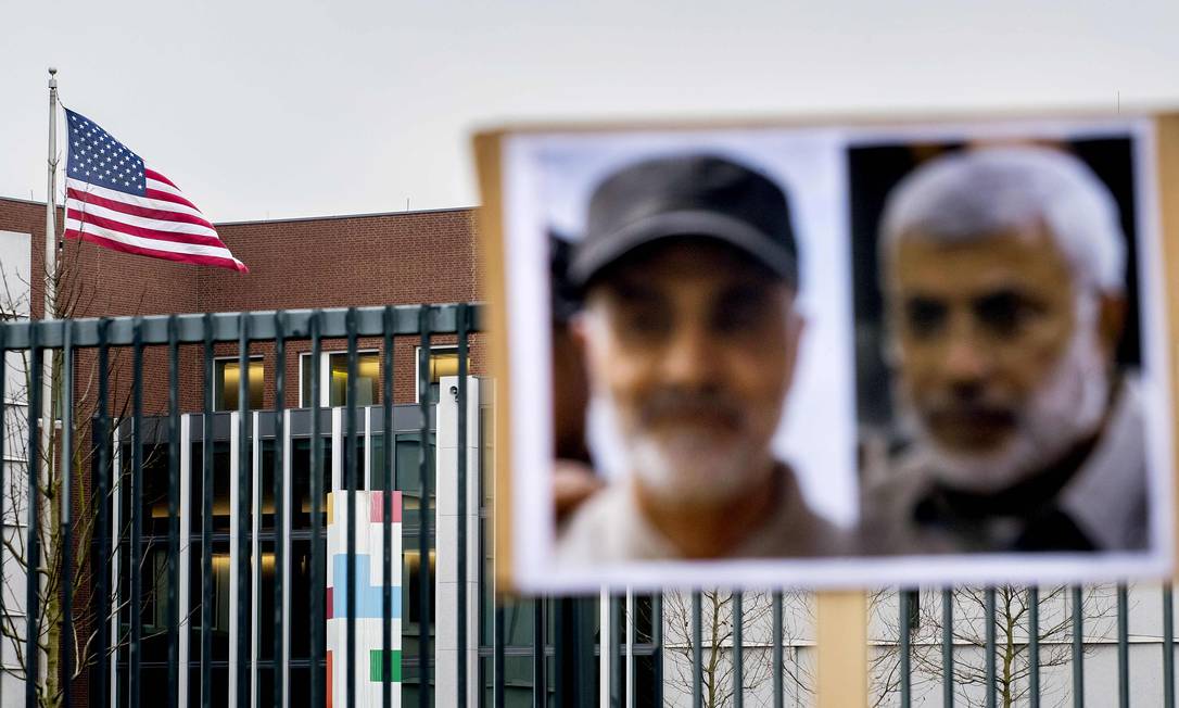 Fotos do general iraniano Qasem Soleimani (E) e do vice-líder de milícia pró-Irã no Iraque Abu Mahdi al-Muhandis, mortos na semana passada em Bagdá, penduradas diante da embaixada americana em Haia, na Holanda Foto: KOEN VAN WEEL / AFP