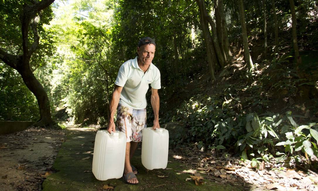 Vardecino de Oliveira carrega 40 litros de água por uma área de mata Foto: Márcia Foletto / Agência O Globo