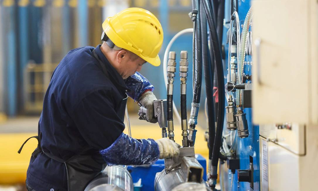 Operário trabalha em uma linha de produção de cilindros em uma fábrica em Hangzhou, na província de Zhejiang, leste da China Foto: STR / AFP