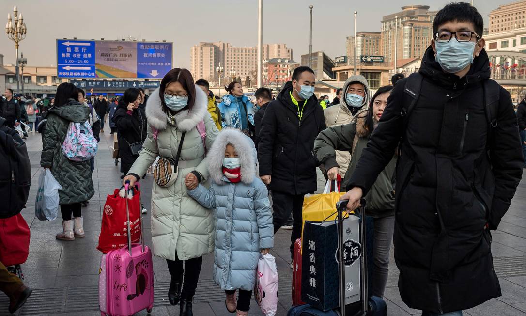 Pessoas caminham na área externa da estação de trem de Pequim vestindo máscaras contra coronavírus, nesta terça-feira (21) Foto: Nicolas Asfouri / AFP