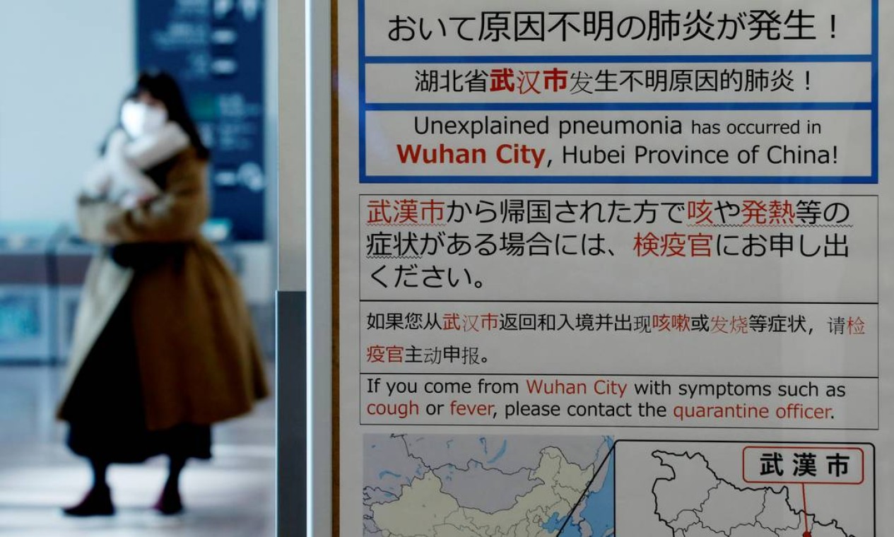 Uma mulher vestindo uma máscara passa por um aviso de quarentena sobre o surto de coronavírus, no saguão de chegada do aeroporto de Haneda em Tóquio, Japão Foto: KIM KYUNG-HOON / REUTERS