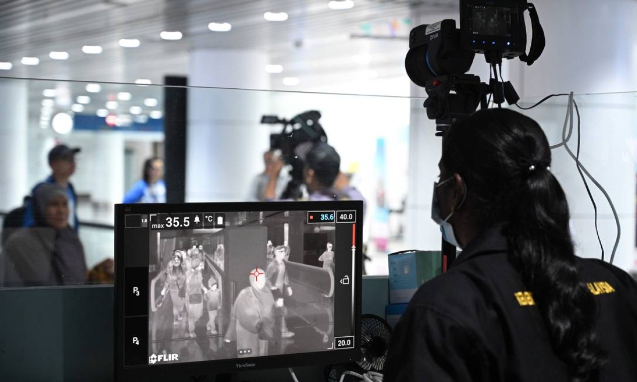 Oficial de saúde da Malásia rastreia passageiros que chegam com um scanner térmico no Aeroporto Internacional de Kuala Lumpur, em Sepang. Autoridades aeroportuárias do mundo todo temem uma pandemia internacional e intensificam a triagem de viajantes da China Foto: MOHD RASFAN / AFP
