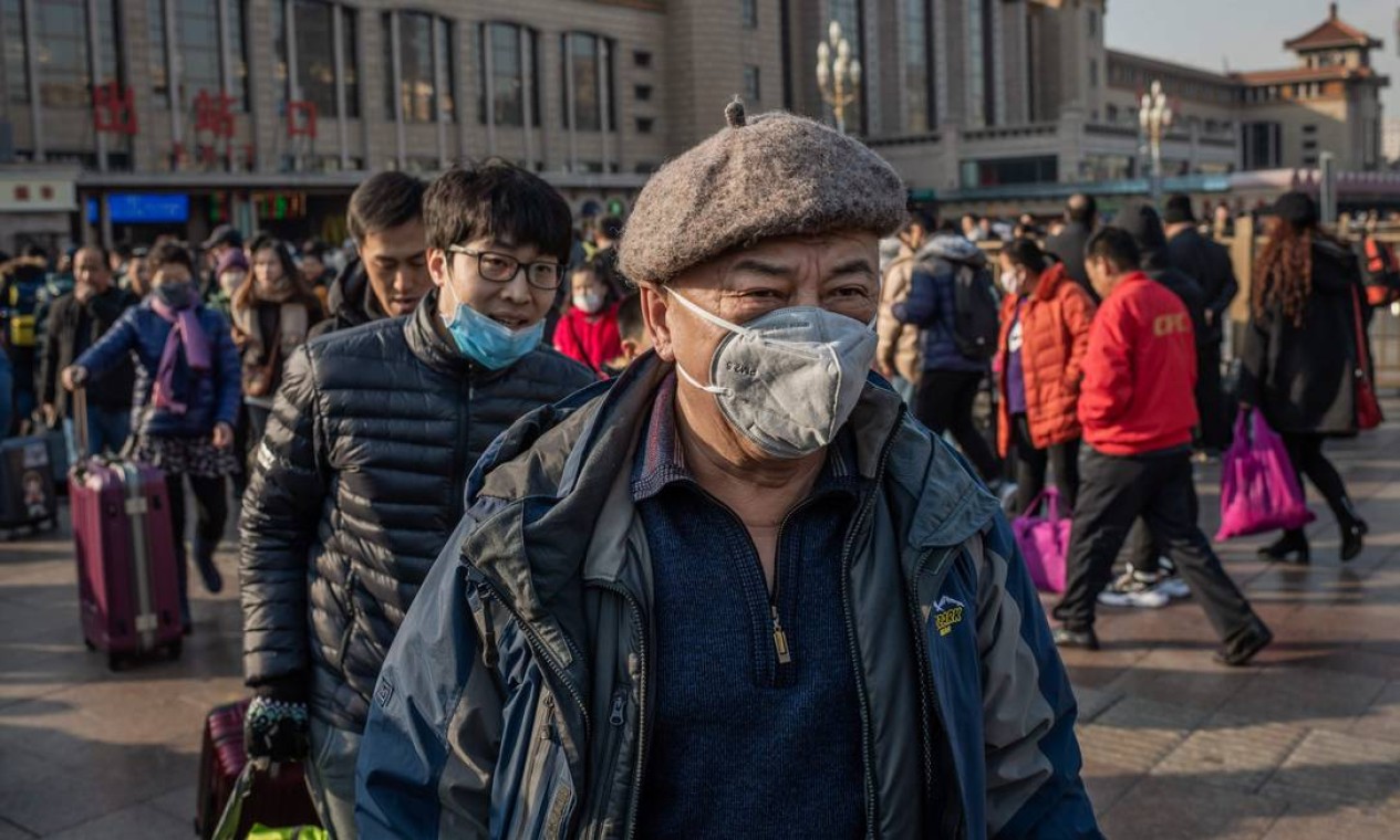 Pessoas usam máscaras protetoras ao chegarem à estação ferroviária de Pequim para voltar para o Ano Novo Lunar. A China confirmou a transmissão do coronavírus de humano para humano Foto: NICOLAS ASFOURI / AFP