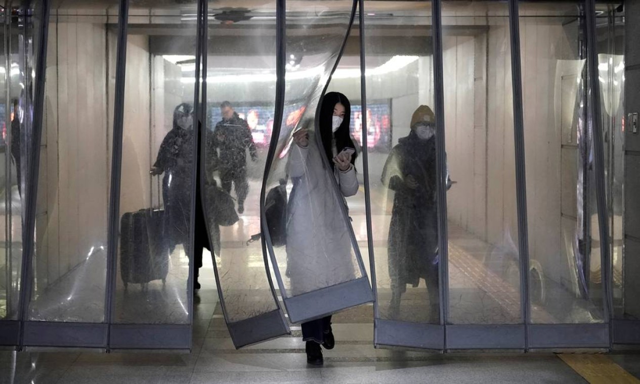 Pessoas com máscaras passam por passagem subterrânea para o metrô em Pequim Foto: JASON LEE / REUTERS